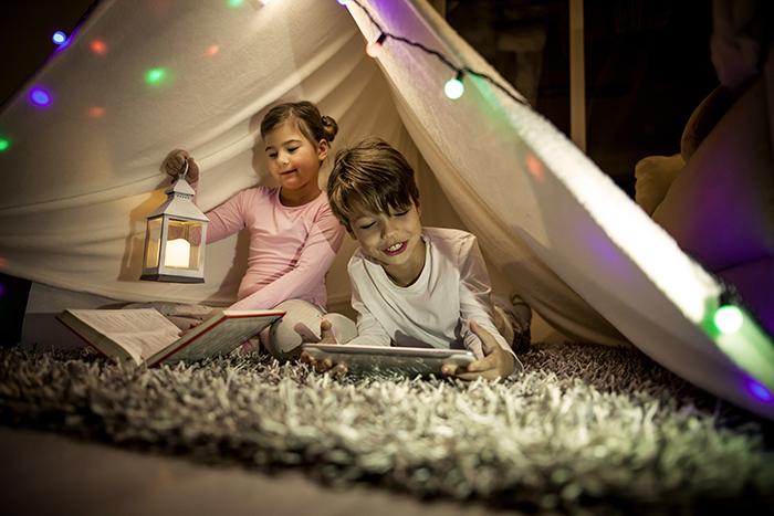 Children with books under makeshift tent indoors