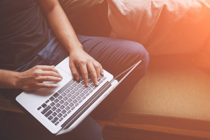 Mans hands typing on a laptop keyboard