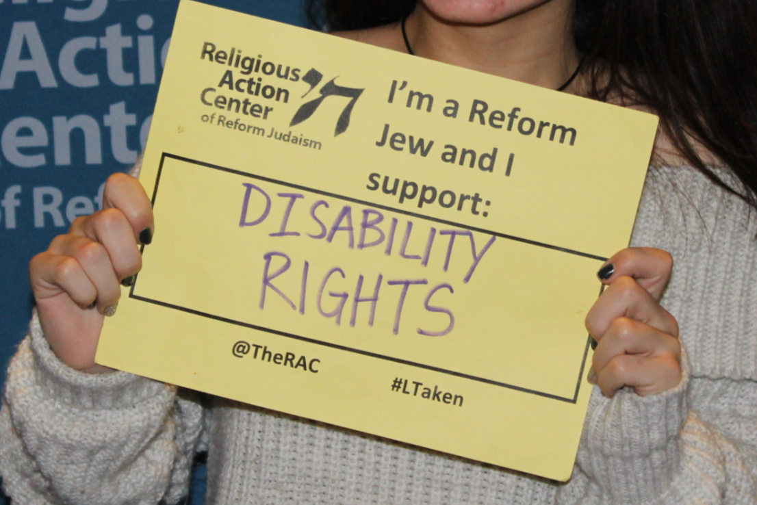 Hands holding a sign reading I AM A REFORM JEW AND I SUPPORT DISABILITY RIGHTS