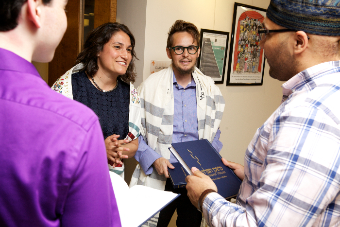 Rabbi smiling and welcoming a small group of people to services