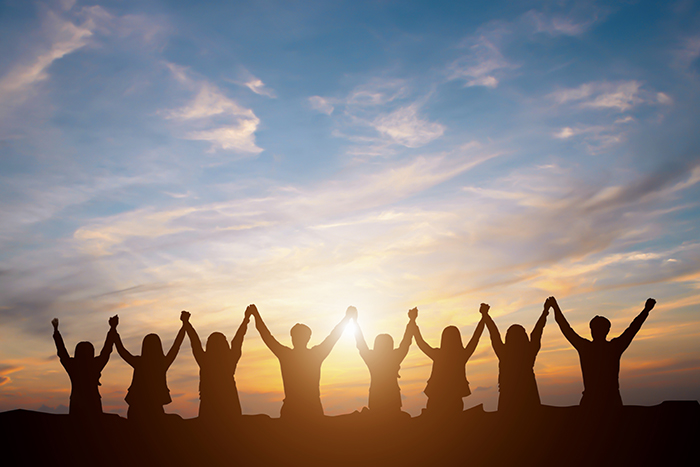 people joining hands at sunset