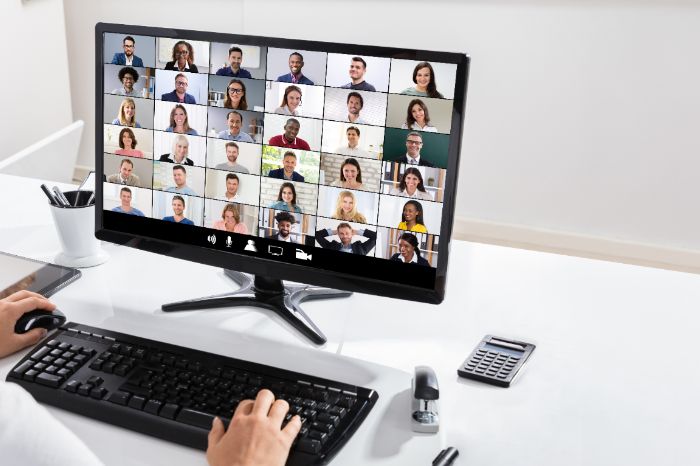 Hands on a keyboard in front of a Zoom screen with a class full of people