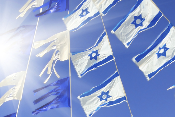 Israeli flags strung up across a blue sky