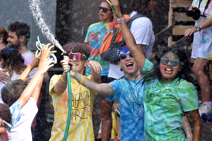 kids at URJ Camp Harlam wearing tie-dye t-shirts an joyfully spraying water on each other with a hose