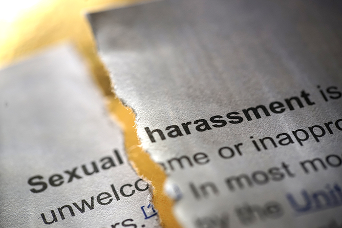 the words sexual harrassment on a torn page in a book