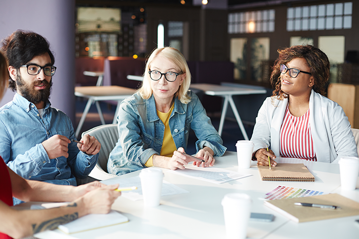 three people sitting around a table in an office