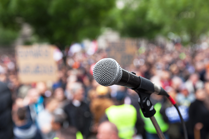 image of a empty microphone in front of a large crowd of people