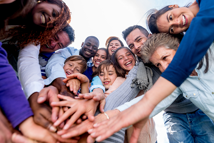 an image of a diverse group of people of different genders, ages, and race in a group holding their hands out in the center on top of each other