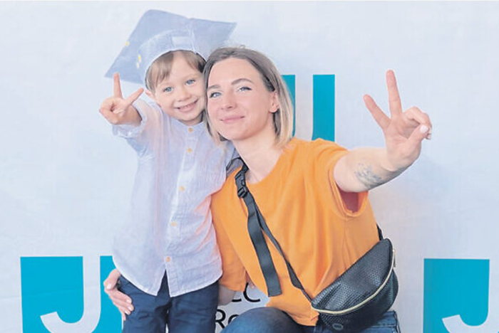 an image of Julia, a young mother working as a restaurant manager in Ukraine, and her son, Sasha, with their arms around each other and holding up peace signs