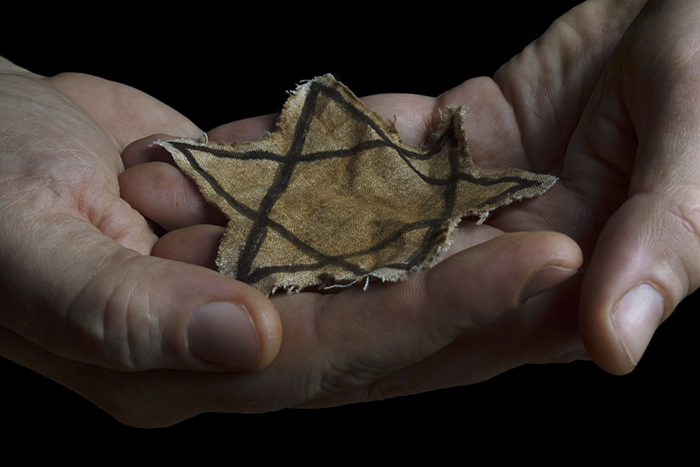 an image of two hands holding a star of david patch from the Holocaust