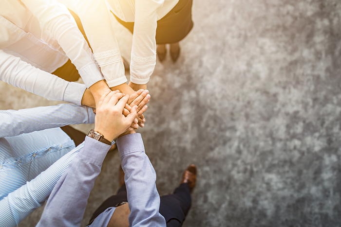 an image of a team huddle with multiple hands stacked on top of each other