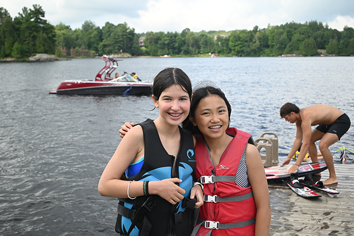 an image of two teens standing in front of a lake