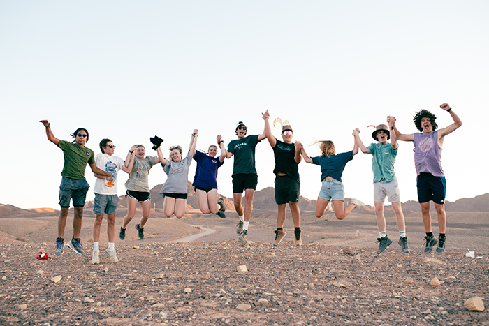 an image of a group of teens jumping in the dessert