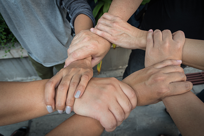 Photo of five hands holding other people's arms in a circle