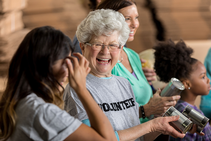 Photo of a older woman smiling and holding a metal can