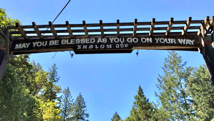 Wooden gate over the trees at URJ Camp Newman reading MAY YOU BE BLESSED AS YOU GO ON YOUR WAY SHALOM