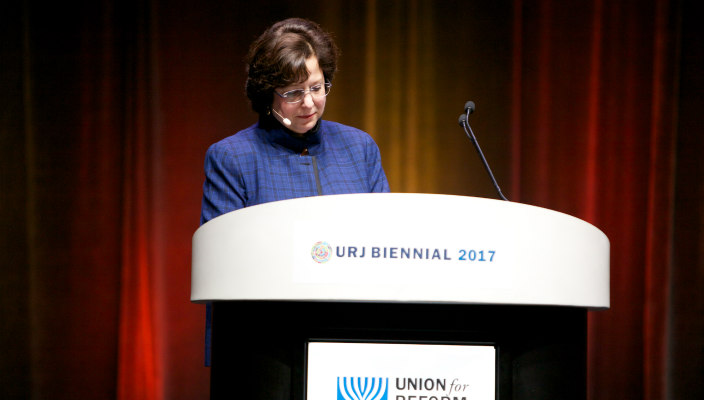 URJ Board Chair Daryl Messinger in a blue blazer standing at the URJ podium