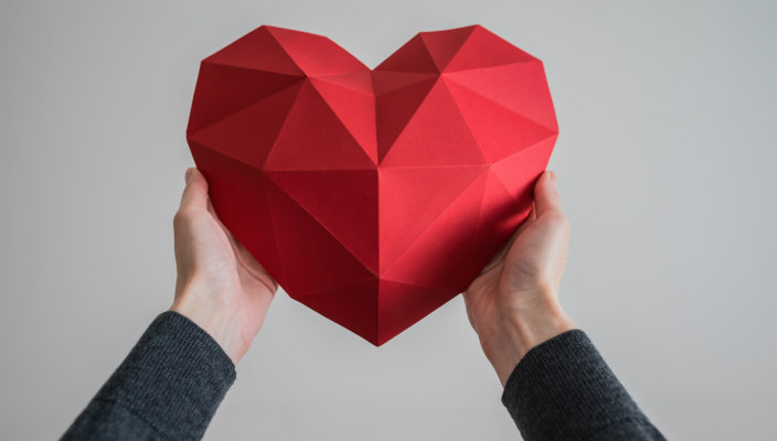 Hands holding a geometric red heart