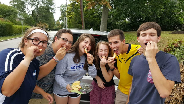 Smiling teens eating apples dipped in honey 