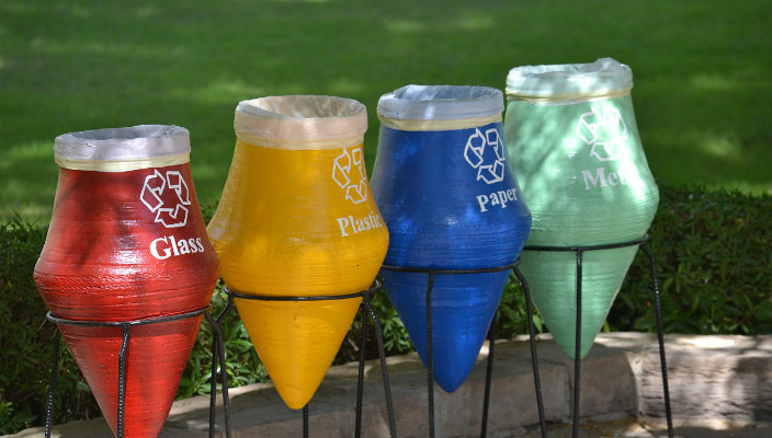 Colorful recycling bins against green grass