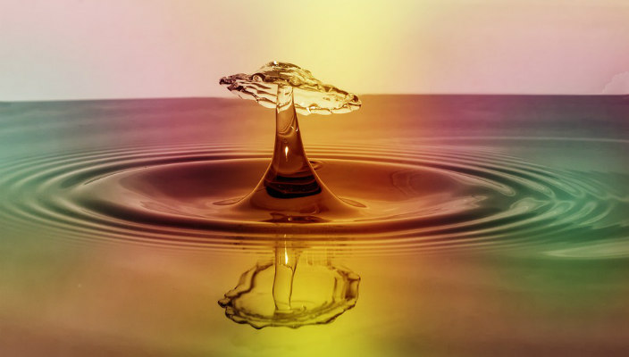 Closeup of a reflective droplet hitting a body of water
