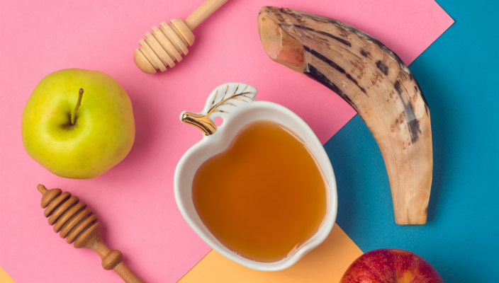 Neon colorblocked background with honey dippers and apples and a shofar