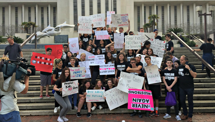 Dozens of teens standing on the Tallahassee Capitol steps wearing PARKLAND STRONG signs and carry gun violence prevention signs