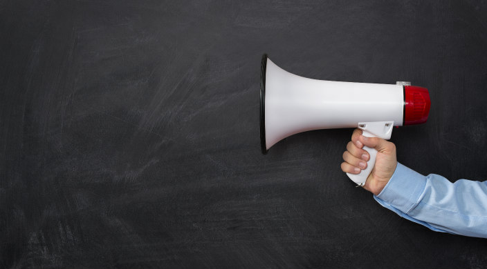 Male hand holding a white megaphone against a chalkboard