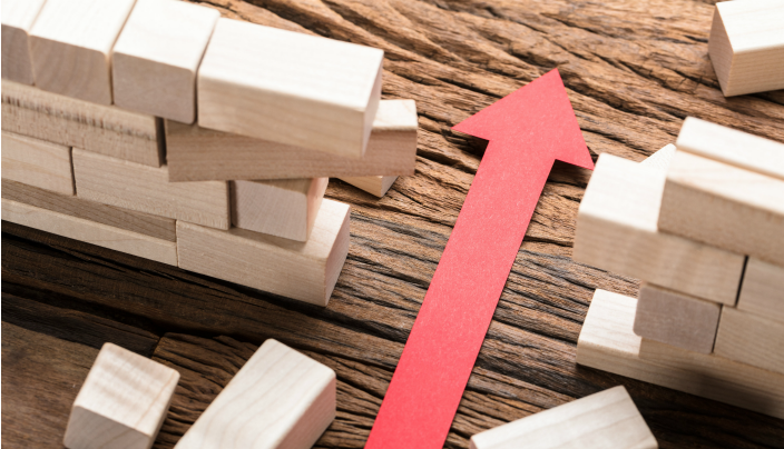 Red arrow breaking through wooden building blocks