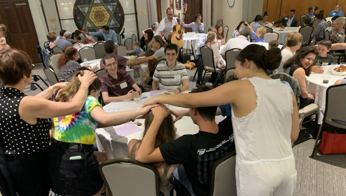 Parents blessing their children at a Shabbat dinner program knows as Challah in the ‘Chood, 