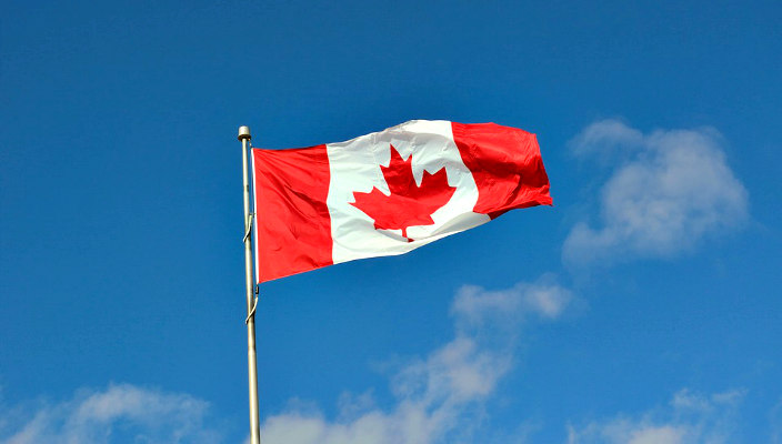 Map of Canada and US; flag of each country is superimposed over the land mass