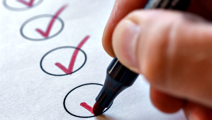 Closeup of a hand holding a red marker above a checklist 