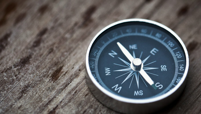 Metal compass on a wooden surface