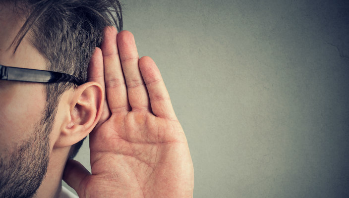 Closeup of a man with a hand to his ear as if listening