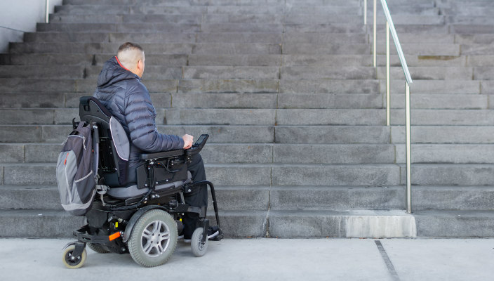 Man in a wheelchair at the bottom of a long flight of steps