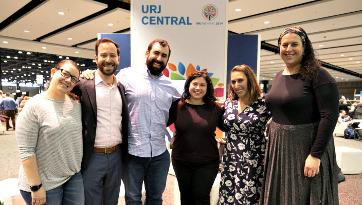 Group of smiling people standing under a sign that reads URJ CENTRAL