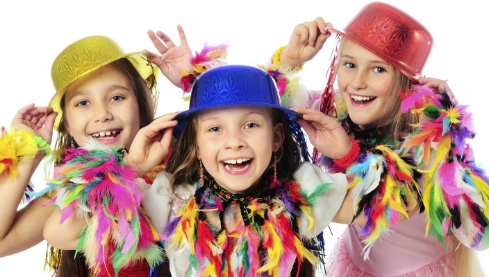 Three pre-teen girls in colorful hats and feathered boas