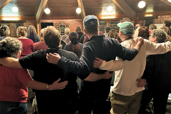 an image of a group of people at Shabbat Shira with their arms around each other