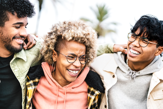 Photo of three people with their arms around each other smiling