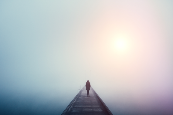 Photo of a Woman crossing a bridge over a lake on a foggy winter day