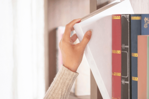 Photo of a hand pulling a book off a shelf