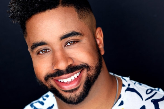Headshot of a smiling Marques Hollie against a black backdrop
