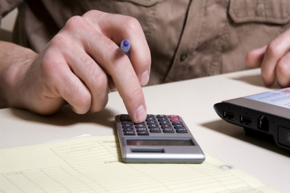 Person with a pen in hand using a calculator