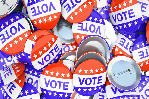 A pile of red, white, and blue buttons that say Vote