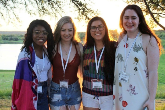 Four teens wearing Judaica and posing with their arms around one another