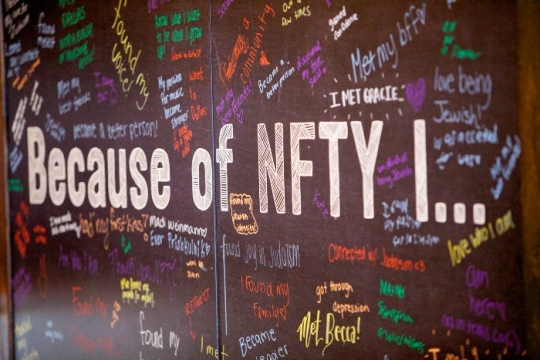 Chalkboard sign reading BEACUSE OF NFTY I surrounded by answers scrawled in colorful chalk