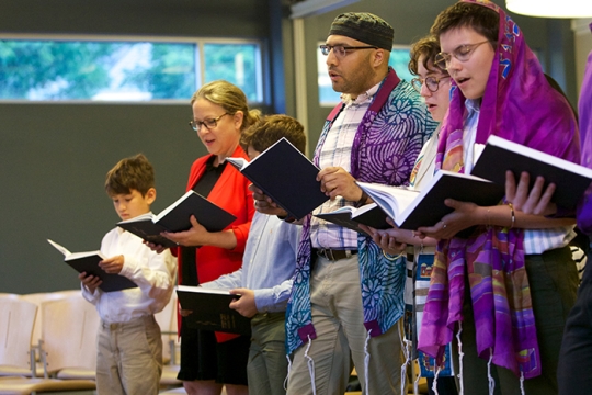 people worshipping with prayer books at Reform Jewish service