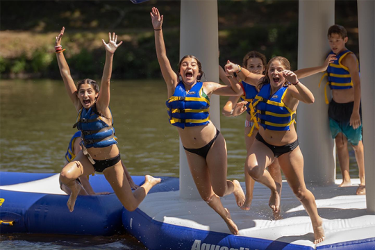 Three Campers Jumping Joyfully into the Lake