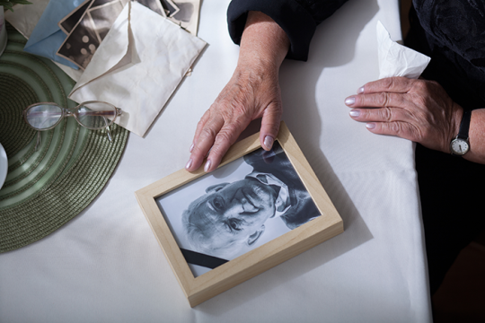 an image of a person's hands on a table touching a picture frame with an image of an older man in it
