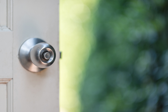 an image of a silver door nob on a white door; door is open